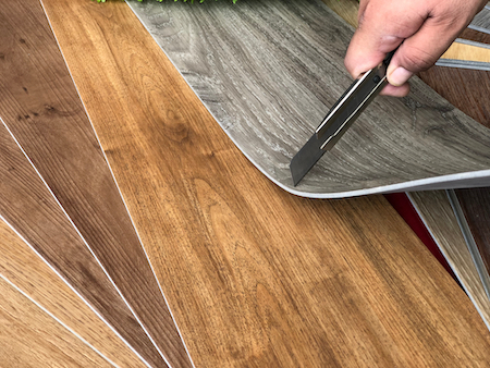 Different types of flooring samples with a hand holding a cutter